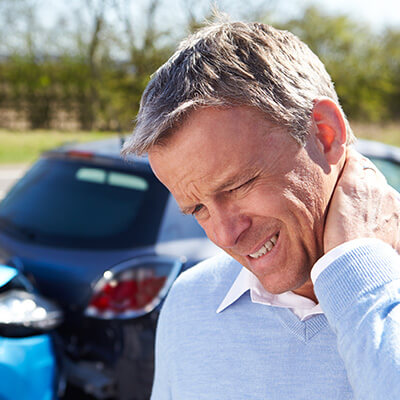 Man standing next to car accident with whiplash Injury in Salem Oregon